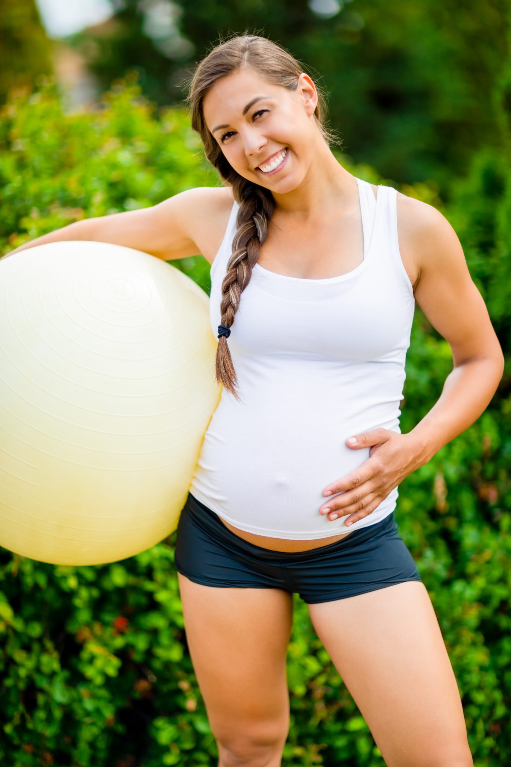 Happy Pregnant Woman Touching Abdomen While Holding Fitness Ball