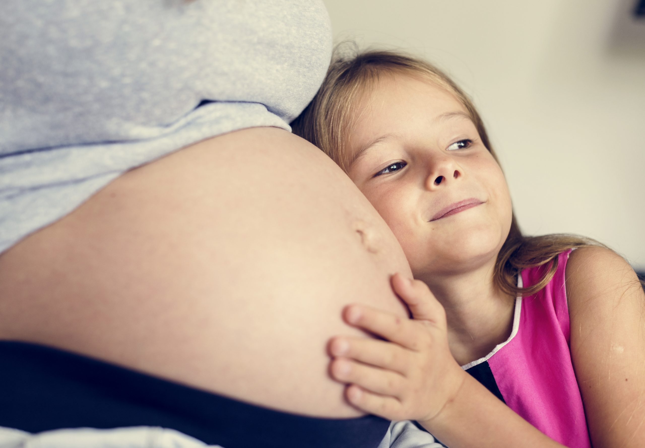 Child touching pregnant woman's stomach